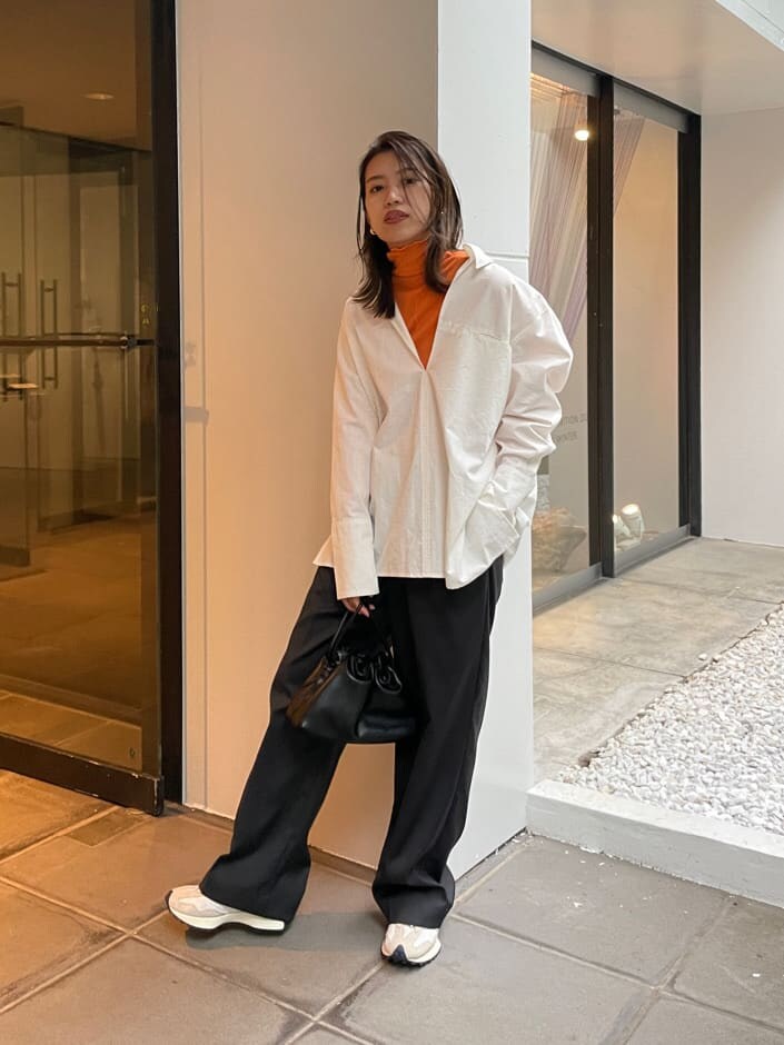 グレー系のスラックス、ホワイト系のシャツ/ブラウス、オレンジ系のTシャツ/カットソーを着用したレディースの秋コーディネートの3枚目の写真