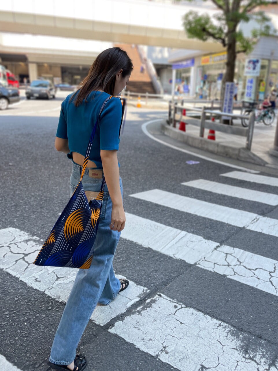 ブルー系のショルダーバッグ、ブルー系のTシャツ/カットソー、ブルー系のデニムパンツを着用したレディースの夏コーディネートの2枚目の写真