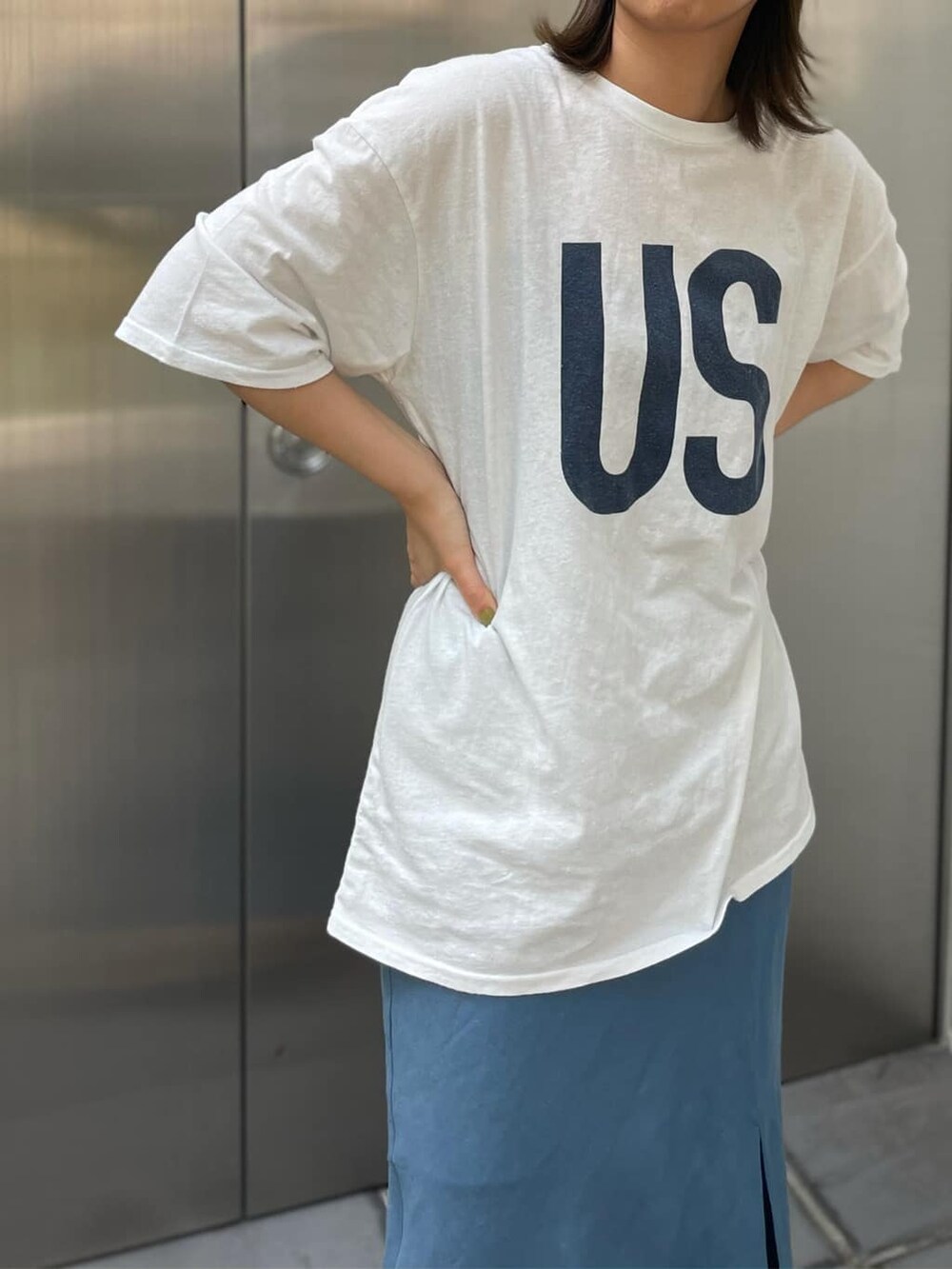 ブルー系のスカート、ブラック系のサンダル、ホワイト系のTシャツ/カットソーを着用したレディースの夏コーディネートの2枚目の写真