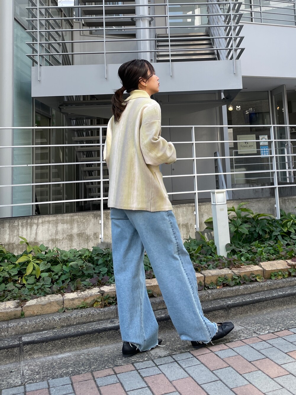 ブルー系のデニムパンツ、グリーン系のカーディガン/ボレロ、ブラック系のパンプスを着用したレディースの秋コーディネートの3枚目の写真