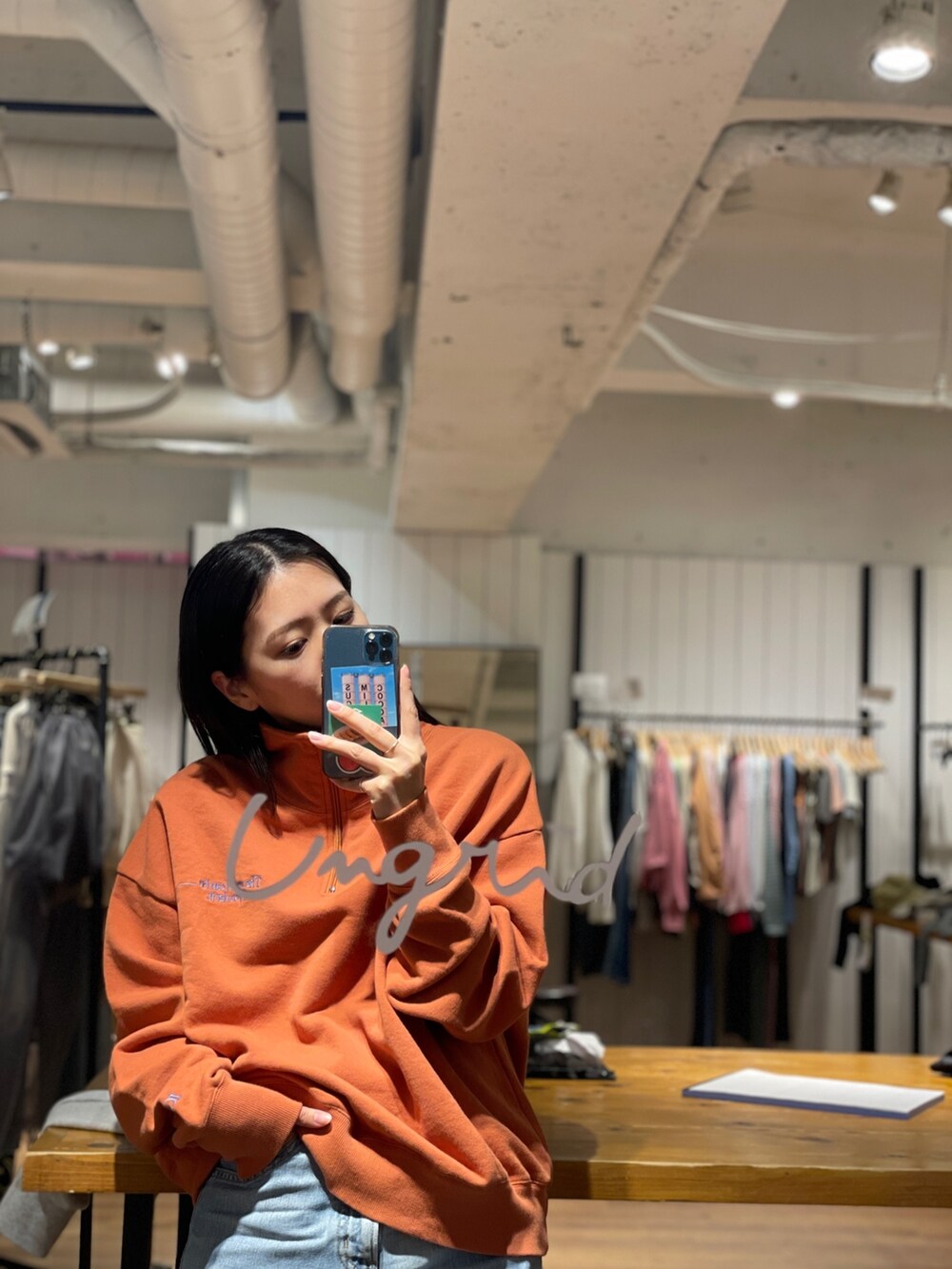 オレンジ系のスウェット、ブルー系のデニムパンツを着用したレディースの冬コーディネートの2枚目の写真