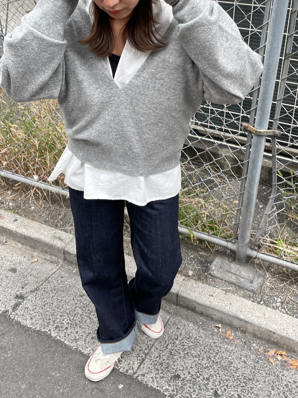 グレー系のニット/セーター、ブルー系のデニムパンツ、ホワイト系のシャツ/ブラウスを着用したレディースの秋コーディネートの3枚目の写真