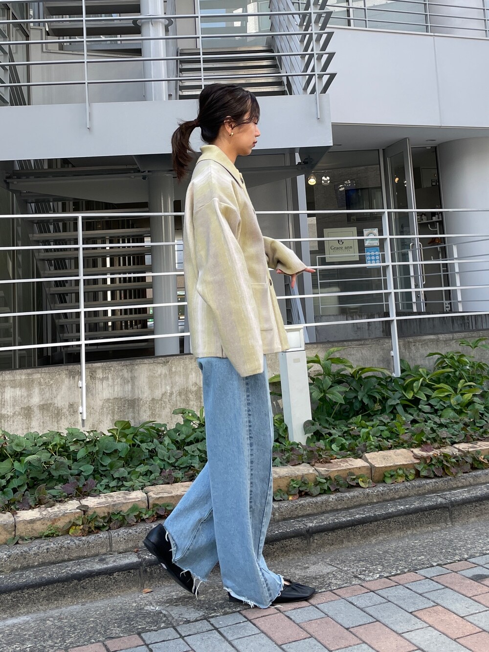 ブルー系のデニムパンツ、グリーン系のカーディガン/ボレロ、ブラック系のパンプスを着用したレディースの秋コーディネートの6枚目の写真