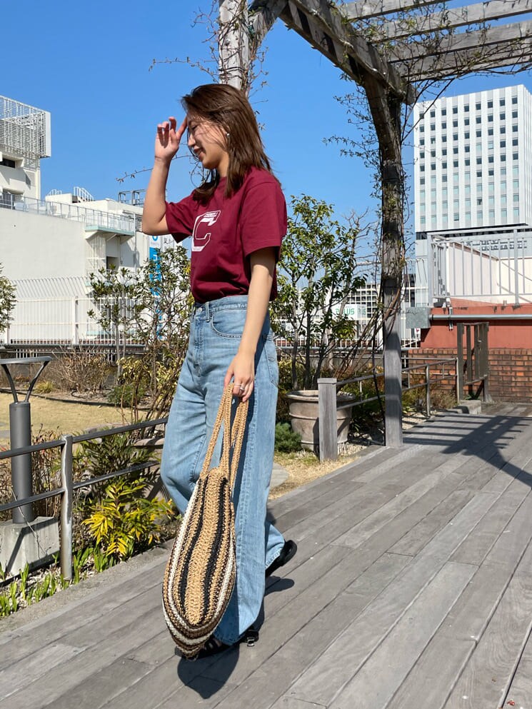 ベージュ系のトートバッグ、ブラック系のサンダル、ブルー系のデニムパンツを着用したレディースの春コーディネートの3枚目の写真