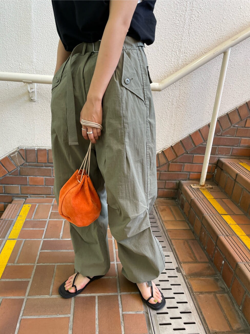 ブラック系のサンダル、オレンジ系のハンドバッグ、ベージュ系のその他パンツを着用したレディースの春コーディネートの9枚目の写真