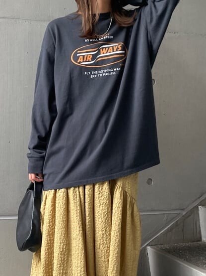 ブラック系のハンドバッグ、グリーン系のスカート、ブラック系のパンプスを着用したレディースの夏コーディネートの9枚目の写真