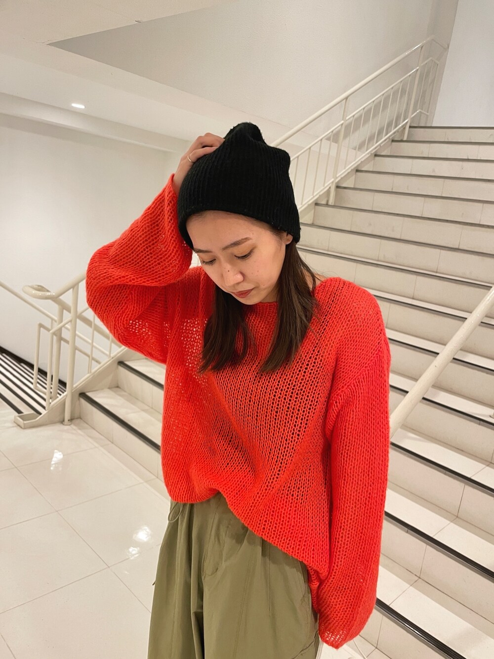 グリーン系のカーゴパンツ、ホワイト系のハンドバッグ、オレンジ系のニット/セーターを着用したレディースの冬コーディネートの6枚目の写真