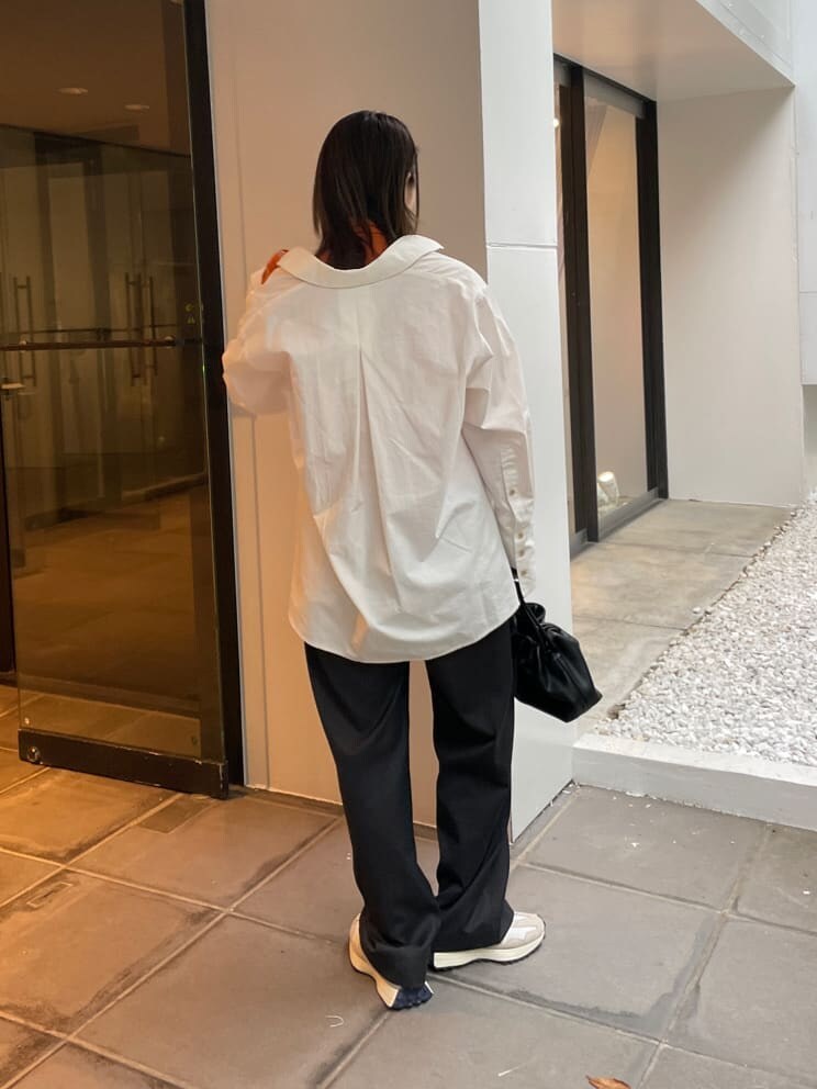 グレー系のスラックス、ホワイト系のシャツ/ブラウス、オレンジ系のTシャツ/カットソーを着用したレディースの秋コーディネートの4枚目の写真