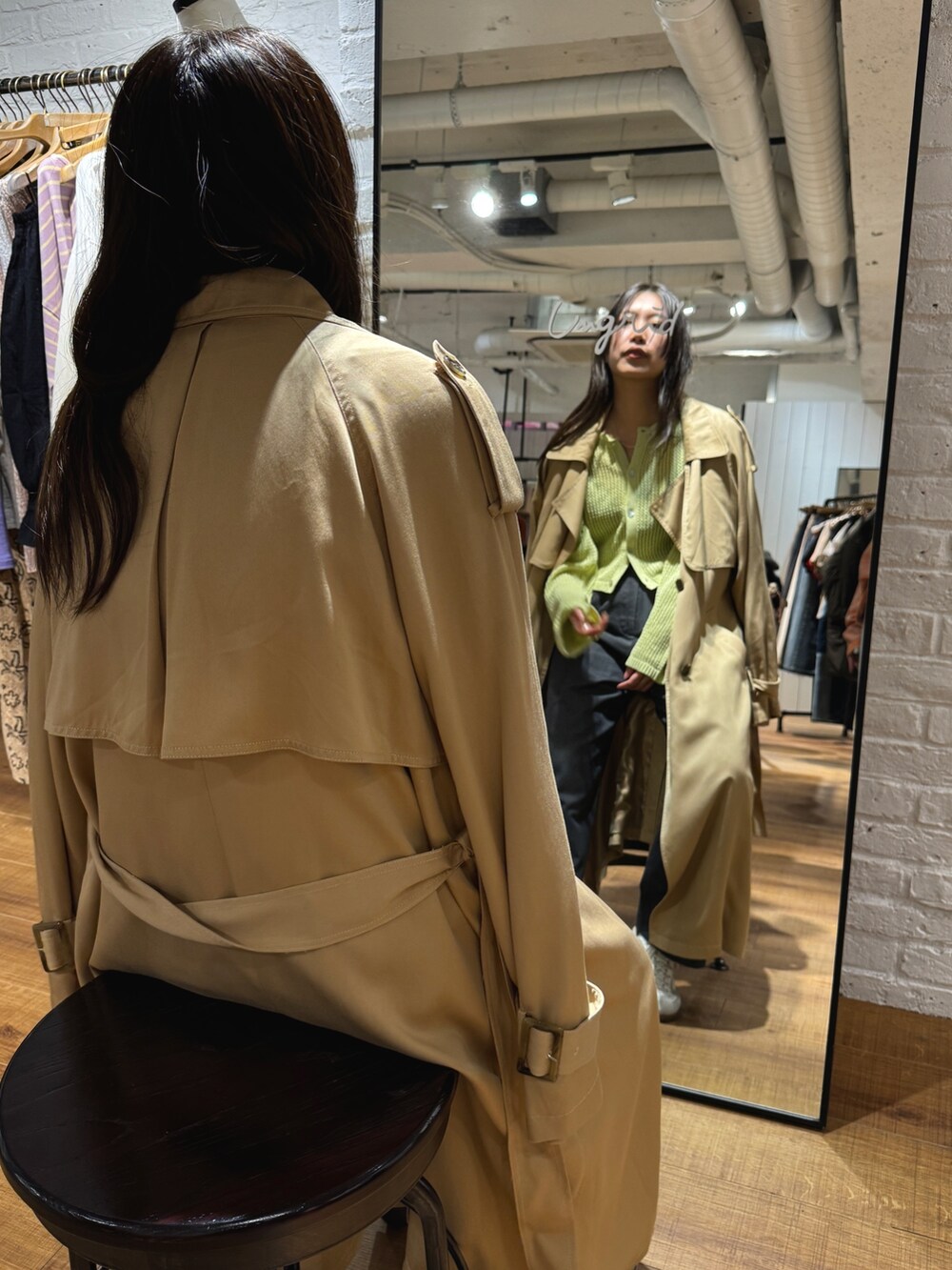 ベージュ系のトレンチコート、グリーン系のカーディガン/ボレロを着用したレディースの冬コーディネートの3枚目の写真