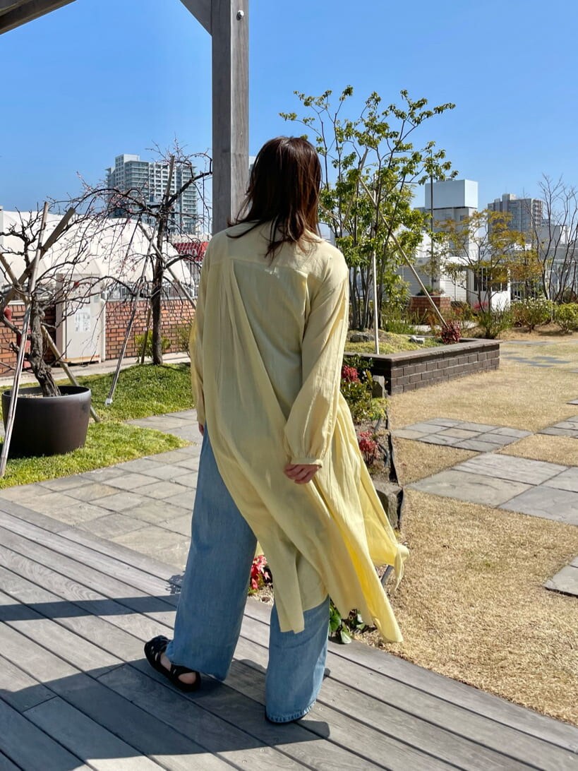 イエロー系のワンピース、ブラック系のサンダル、ブルー系のデニムパンツを着用したレディースの春コーディネートの3枚目の写真