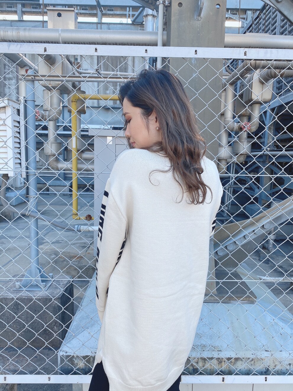 ブラック系のデニムパンツ、ホワイト系のニット/セーターを着用したレディースの冬コーディネートの2枚目の写真