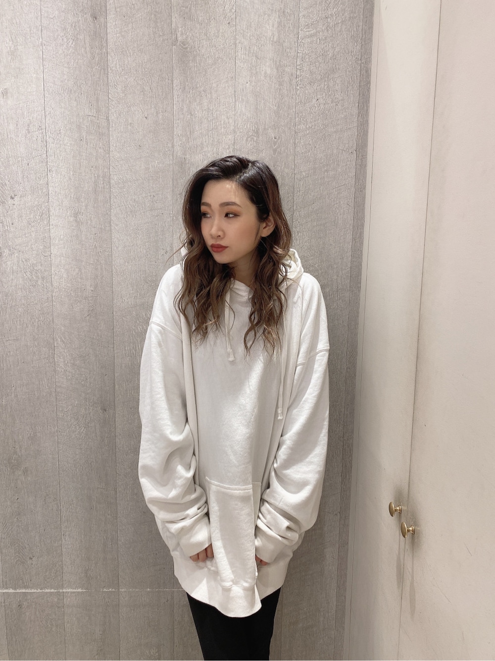 ホワイト系のパーカー、ブラック系のレギンス/スパッツを着用したレディースの冬コーディネートの2枚目の写真