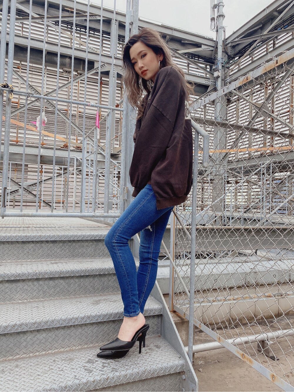 ブラック系のパンプス、ブルー系のデニムパンツを着用したレディースの冬コーディネートの2枚目の写真