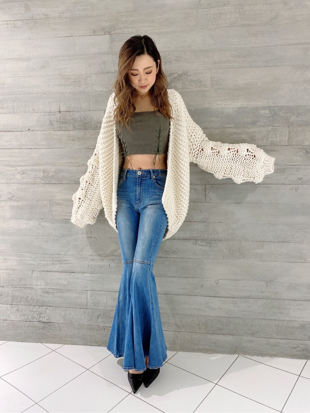 ブラック系のパンプス、ブルー系のデニムパンツ、ベージュ系のキャミソールを着用したレディースの冬コーディネートの3枚目の写真