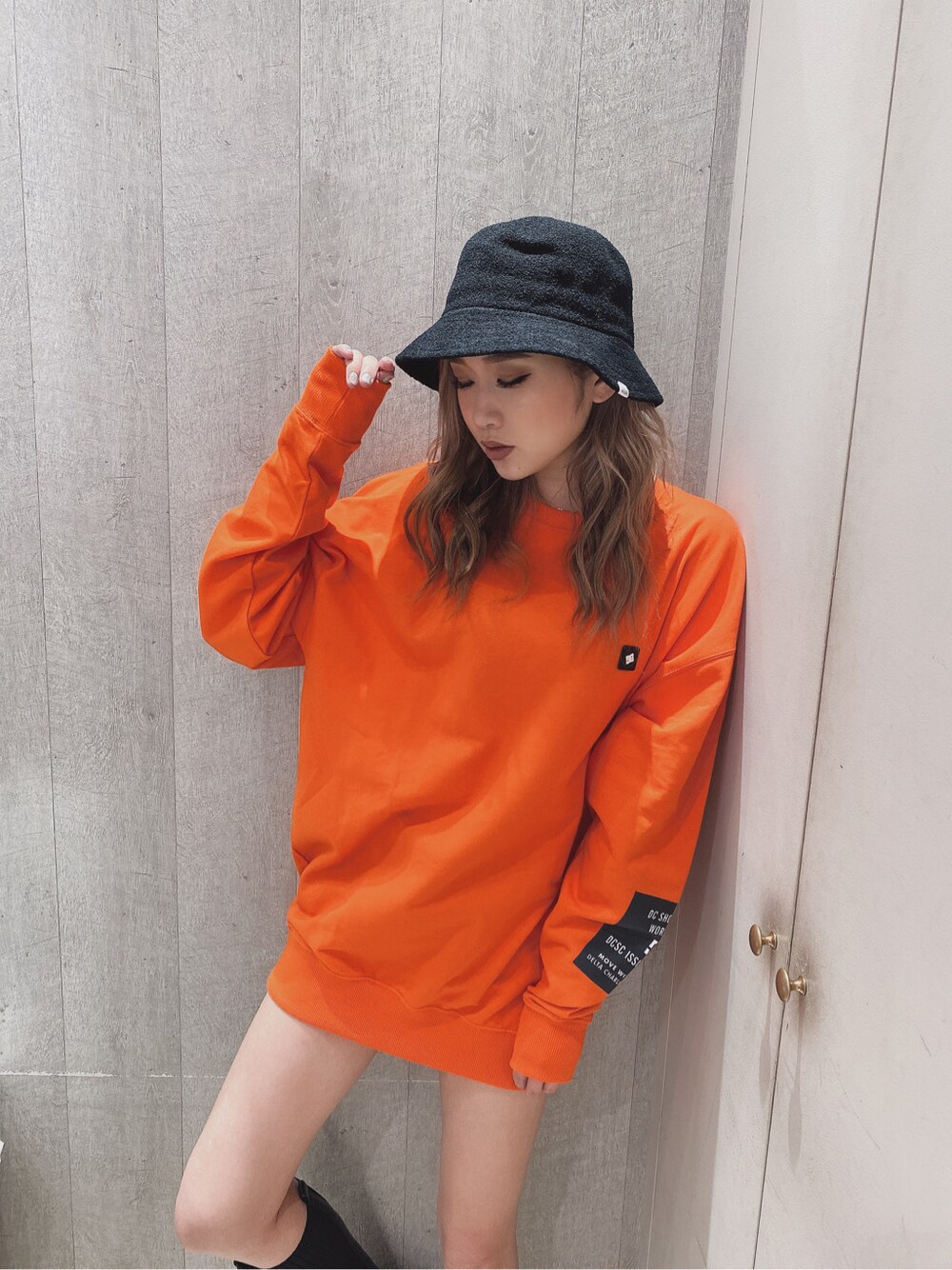 オレンジ系のスウェットを着用したレディースの秋コーディネートの2枚目の写真