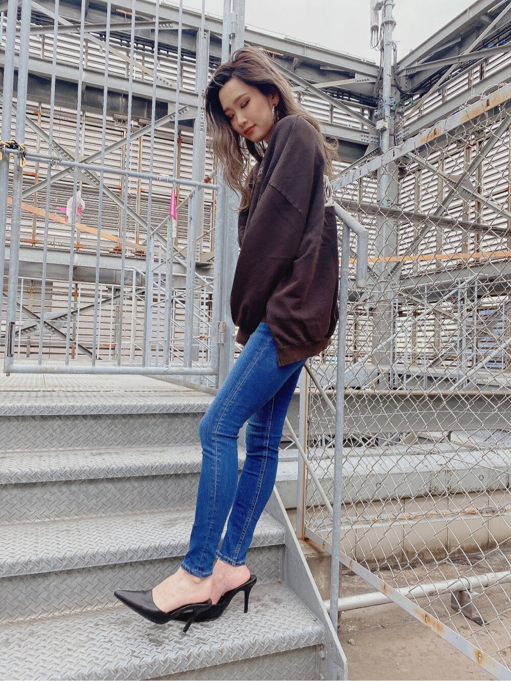 ブラック系のパンプス、ブルー系のデニムパンツを着用したレディースの冬コーディネートの3枚目の写真