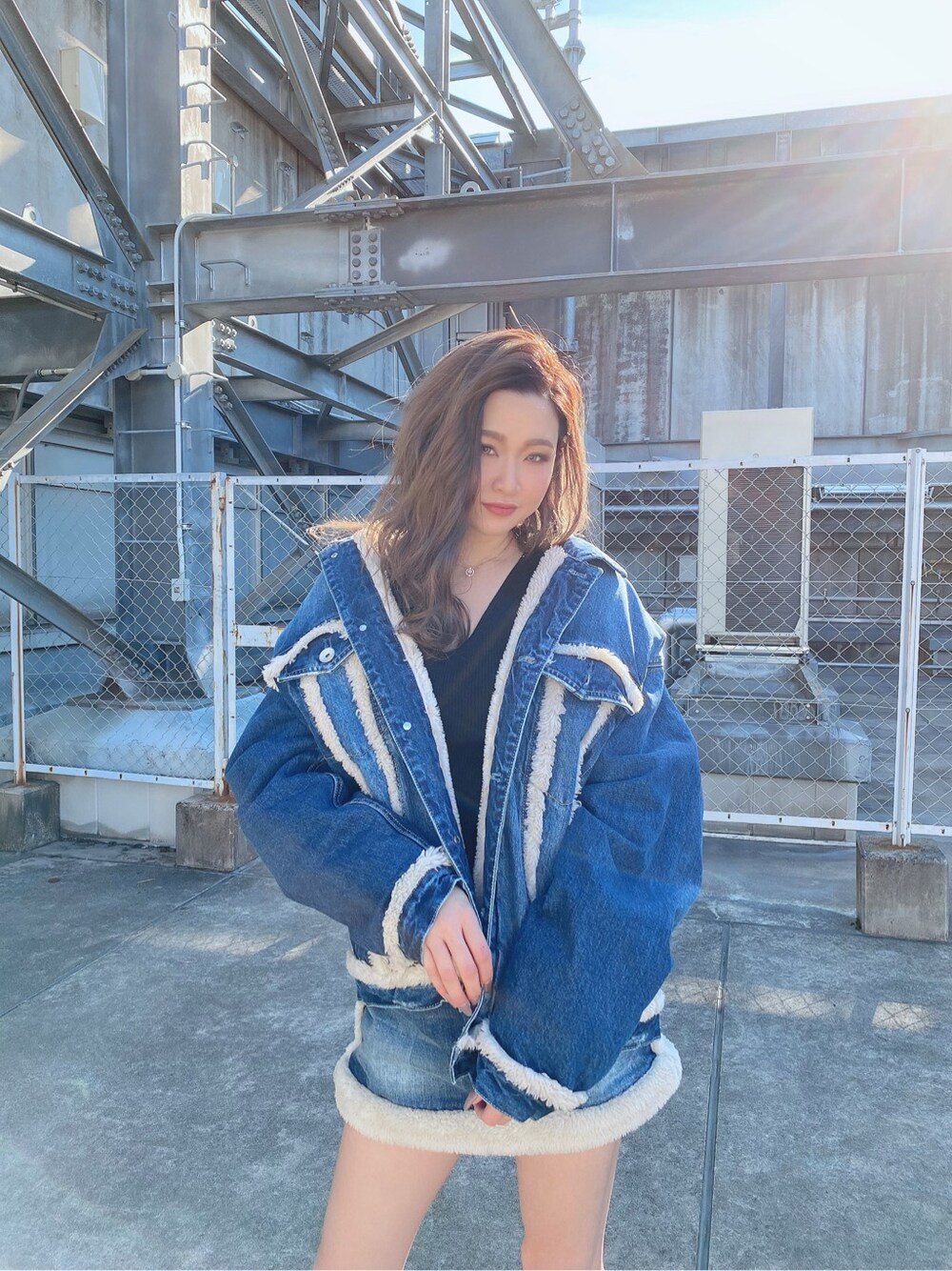 ブラック系のニット/セーター、ブルー系のデニムジャケット、ブルー系のデニムスカートを着用したレディースの冬コーディネートの2枚目の写真