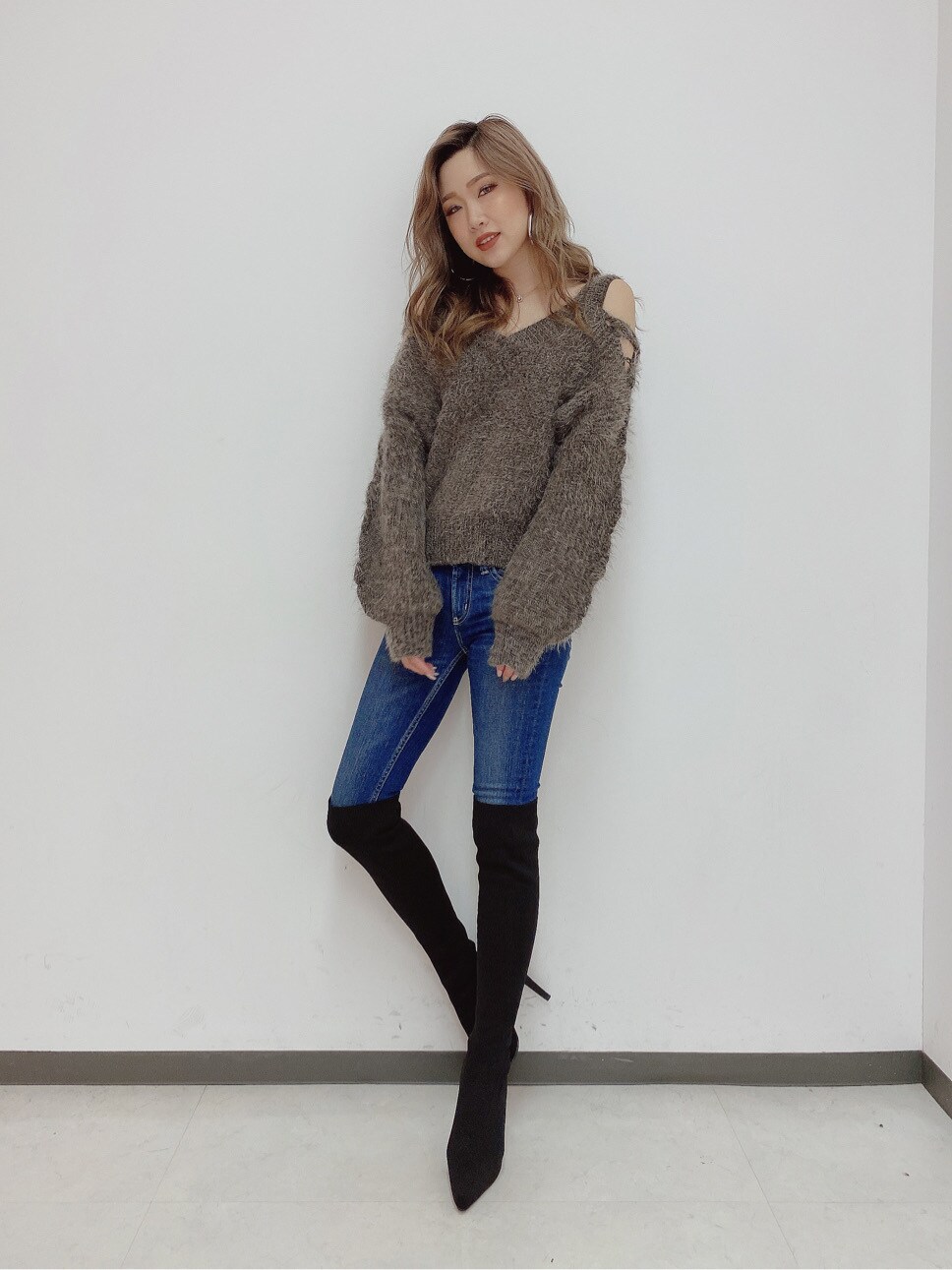 ブルー系のデニムパンツ、グレー系のニット/セーター、ブラック系のブーツを着用したレディースの秋コーディネートの2枚目の写真