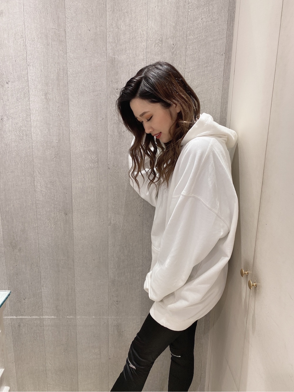 ホワイト系のパーカー、ブラック系のレギンス/スパッツを着用したレディースの冬コーディネートの3枚目の写真