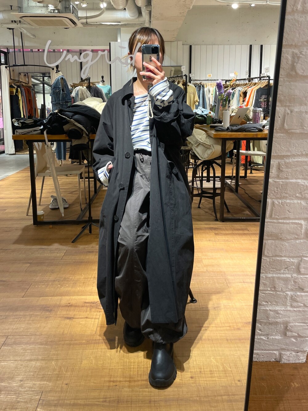 ブラック系のステンカラーコート、ホワイト系のTシャツ/カットソー、グレー系のその他パンツを着用したレディースの冬コーディネートの2枚目の写真