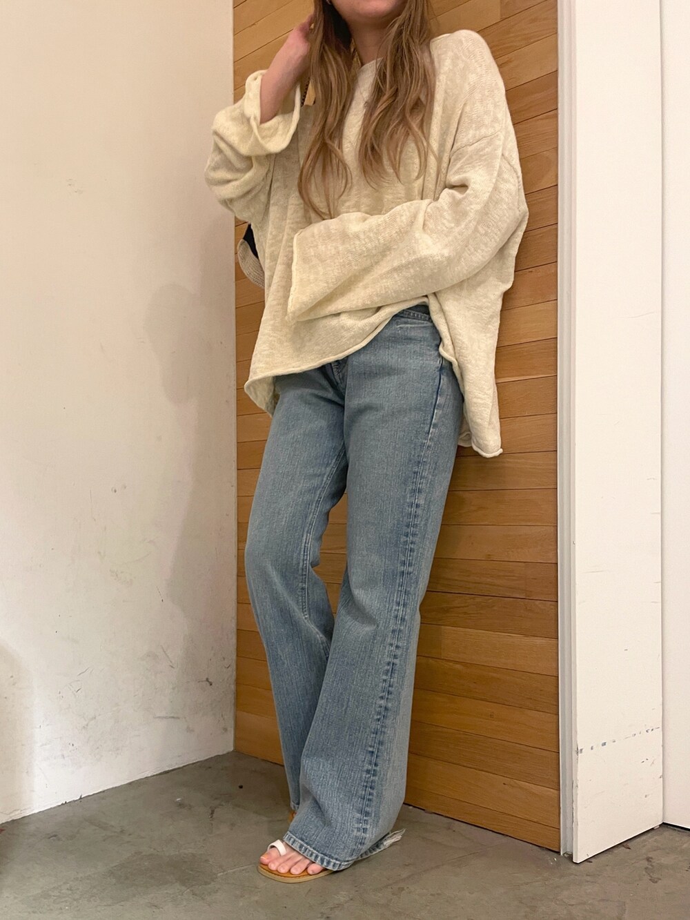 ホワイト系のニット/セーター、ブルー系のデニムパンツ、ホワイト系のハンドバッグを着用したレディースの冬コーディネートの2枚目の写真