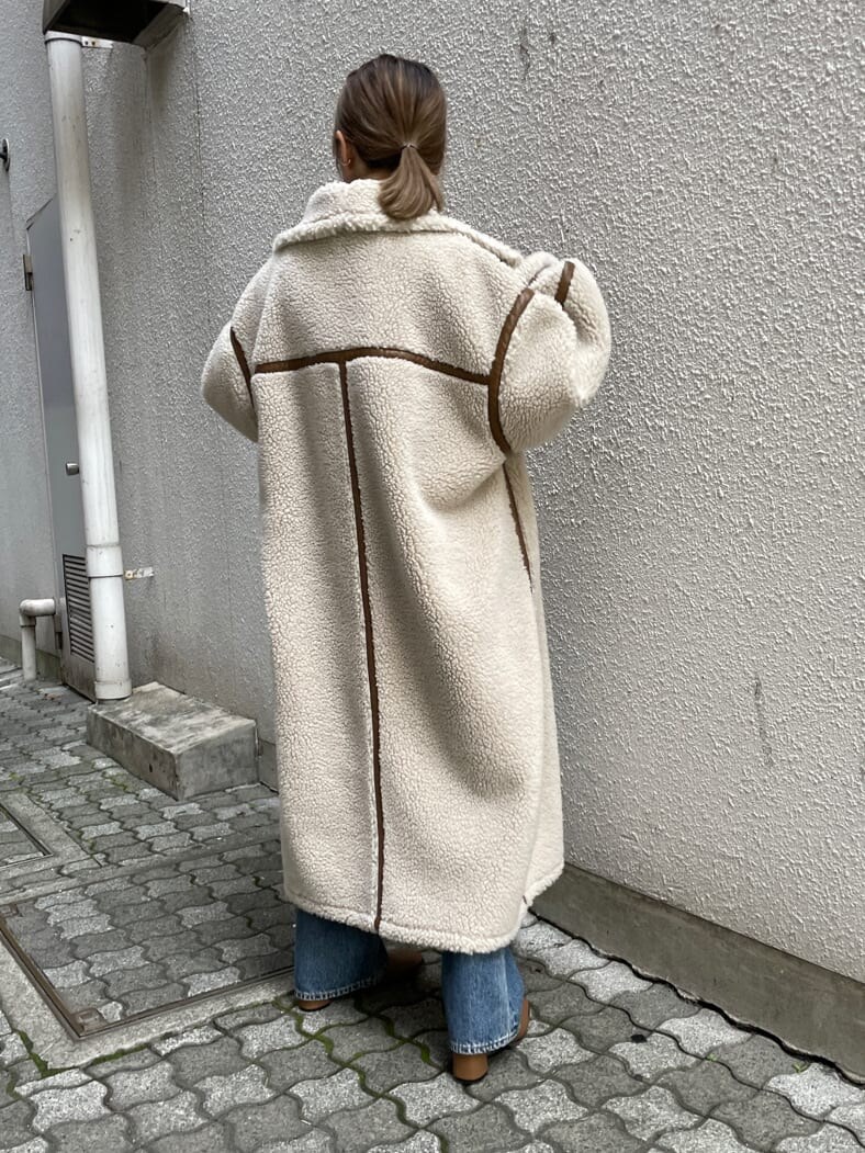 ホワイト系のムートンコート、ブラウン系のブーツ、グリーン系のTシャツ/カットソーを着用したレディースの夏コーディネートの2枚目の写真