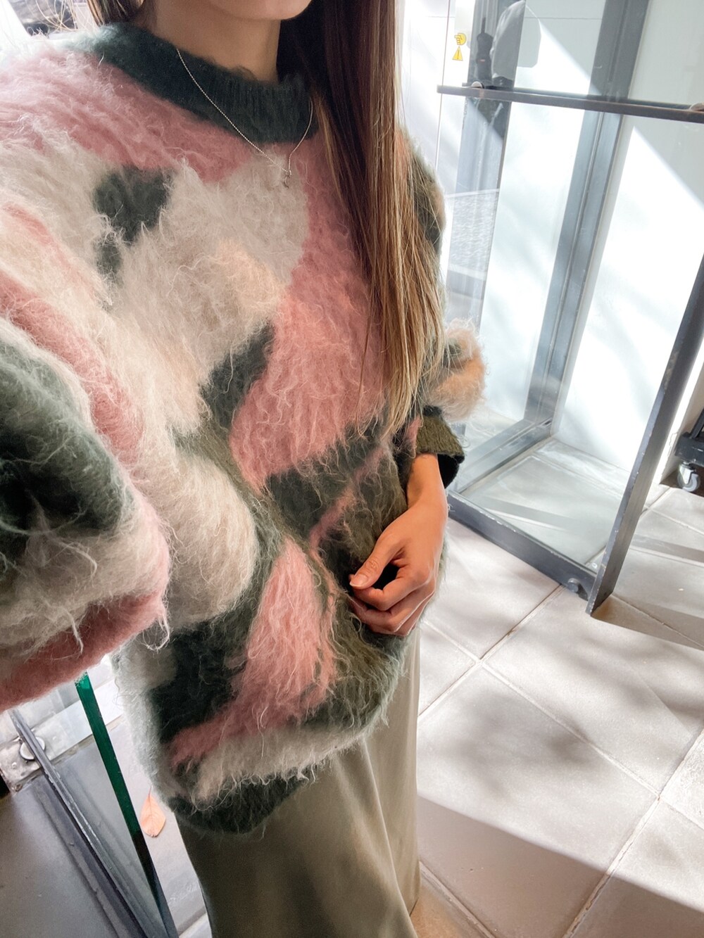 グレー系のスカート、グリーン系のニット/セーターを着用したレディースの冬コーディネートの2枚目の写真