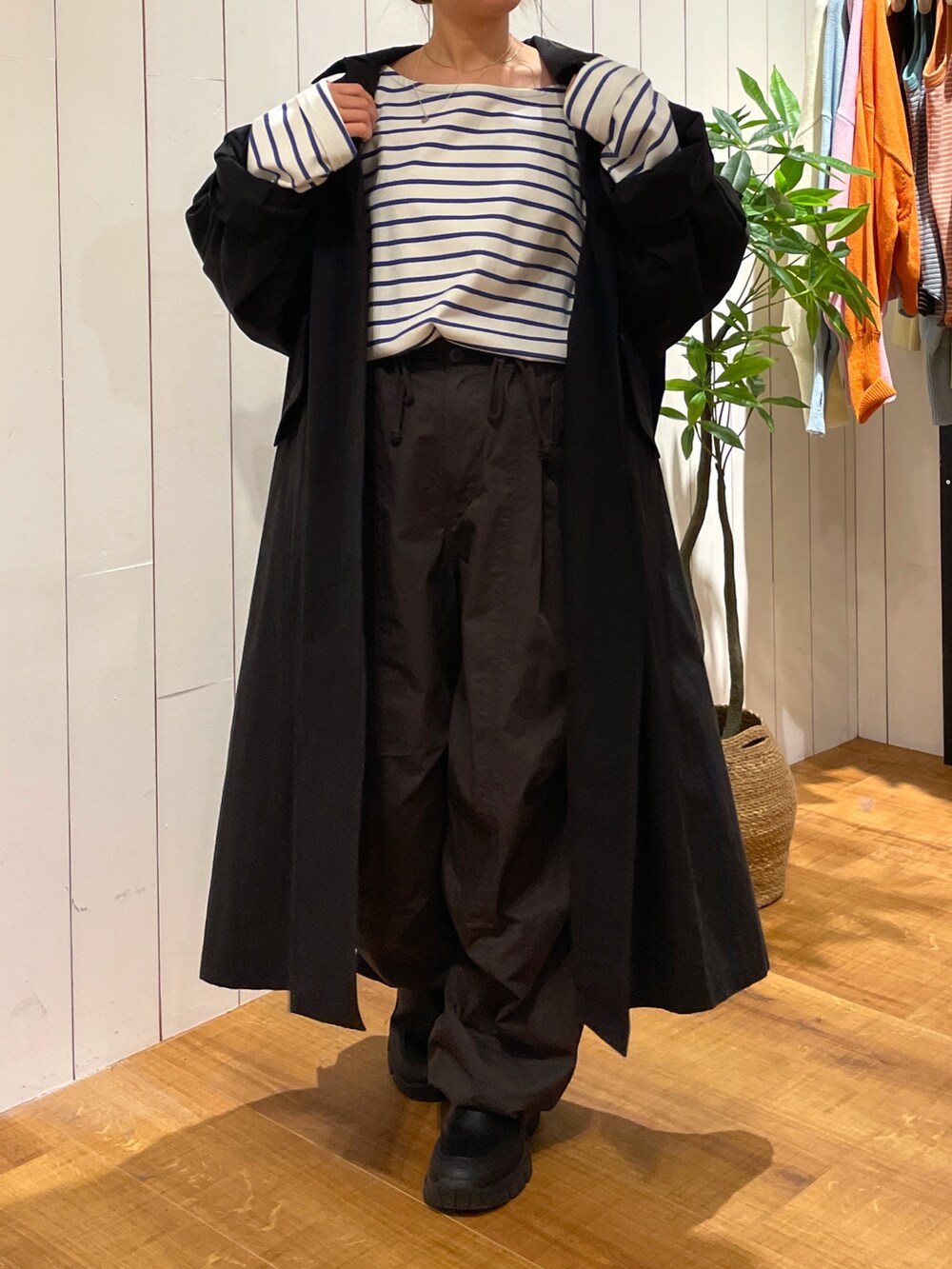 ブラック系のステンカラーコート、ホワイト系のTシャツ/カットソー、グレー系のその他パンツを着用したレディースの冬コーディネートの4枚目の写真