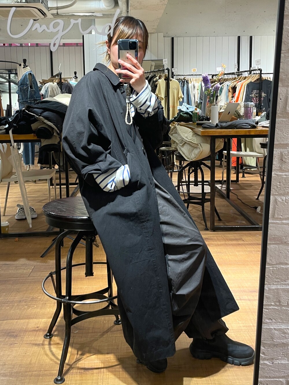 ブラック系のステンカラーコート、ホワイト系のTシャツ/カットソー、グレー系のその他パンツを着用したレディースの冬コーディネートの3枚目の写真