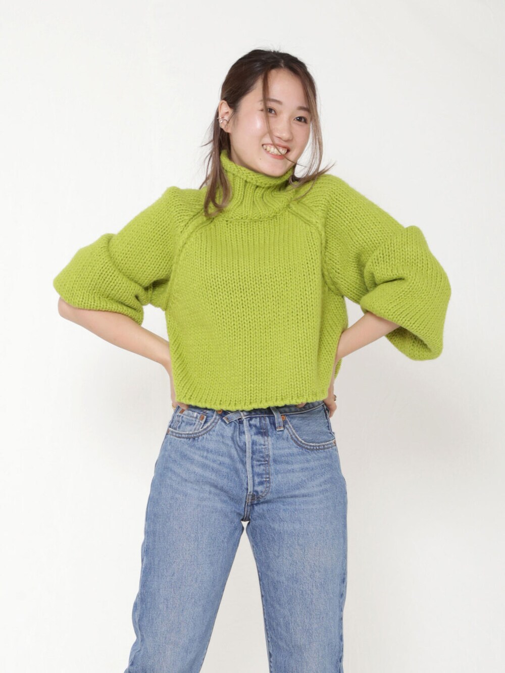 ブルー系のデニムパンツ、ホワイト系のブーツ、イエロー系のクラッチバッグを着用したレディースの秋コーディネートの3枚目の写真