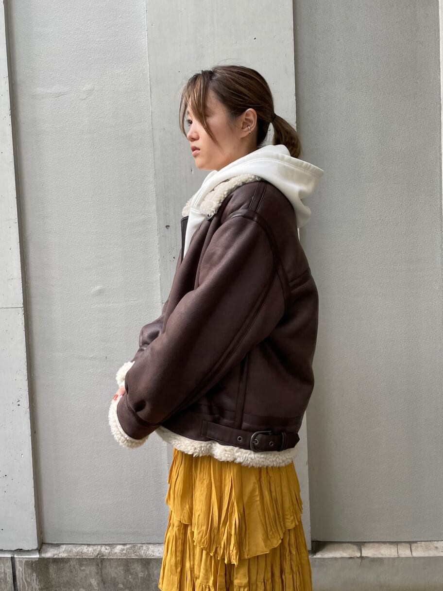 ブラウン系のブルゾン、イエロー系のスカート、ホワイト系のパーカーを着用したレディースの夏コーディネートの2枚目の写真