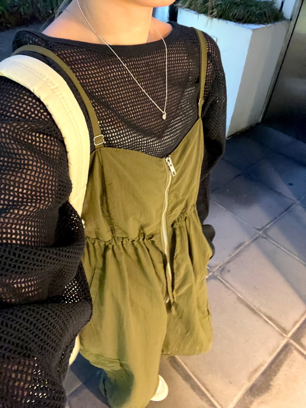 グレー系のTシャツ/カットソー、ベージュ系のバックパック/リュック、グリーン系のサロペット/オーバーオールを着用したレディースの冬コーディネートの2枚目の写真