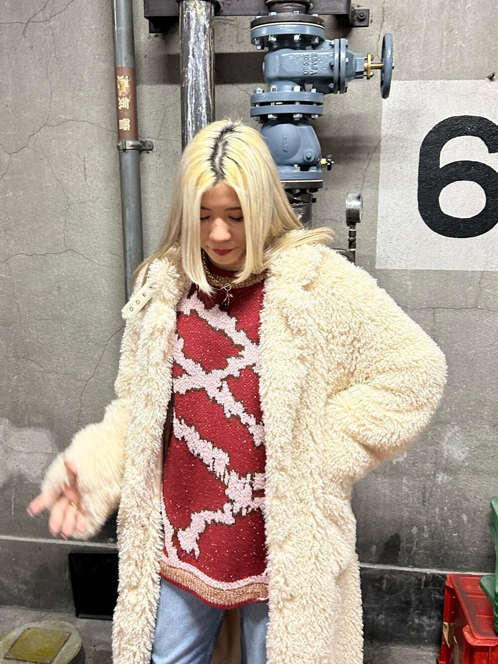 レッド系のニット/セーター、ブルー系のデニムパンツ、ホワイト系のその他アウターを着用したレディースの冬コーディネートの3枚目の写真