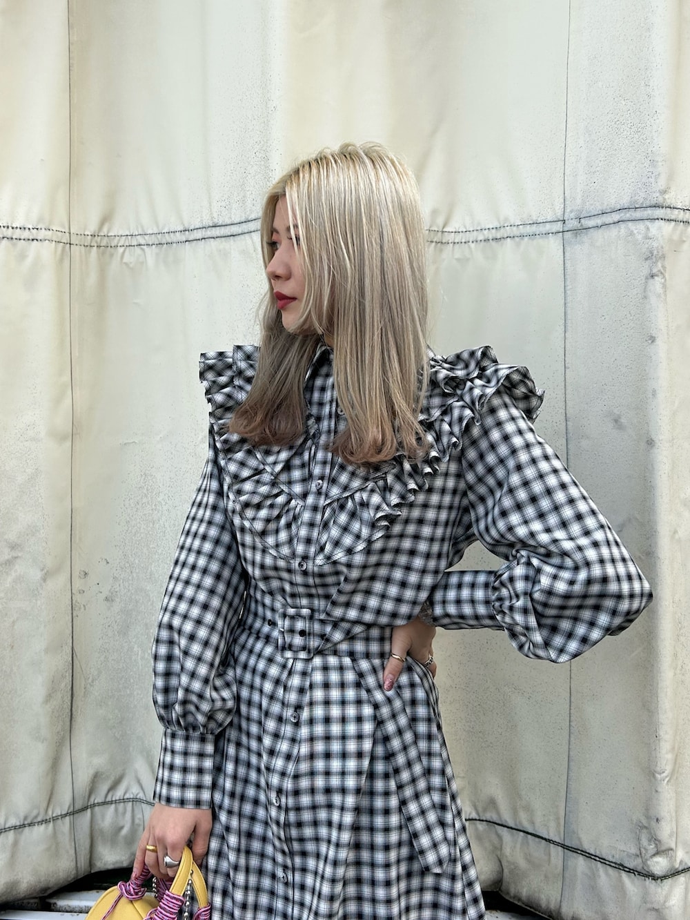 ブラック系のブーツ、イエロー系のショルダーバッグ、ブラック系のワンピースを着用したレディースの冬コーディネートの3枚目の写真