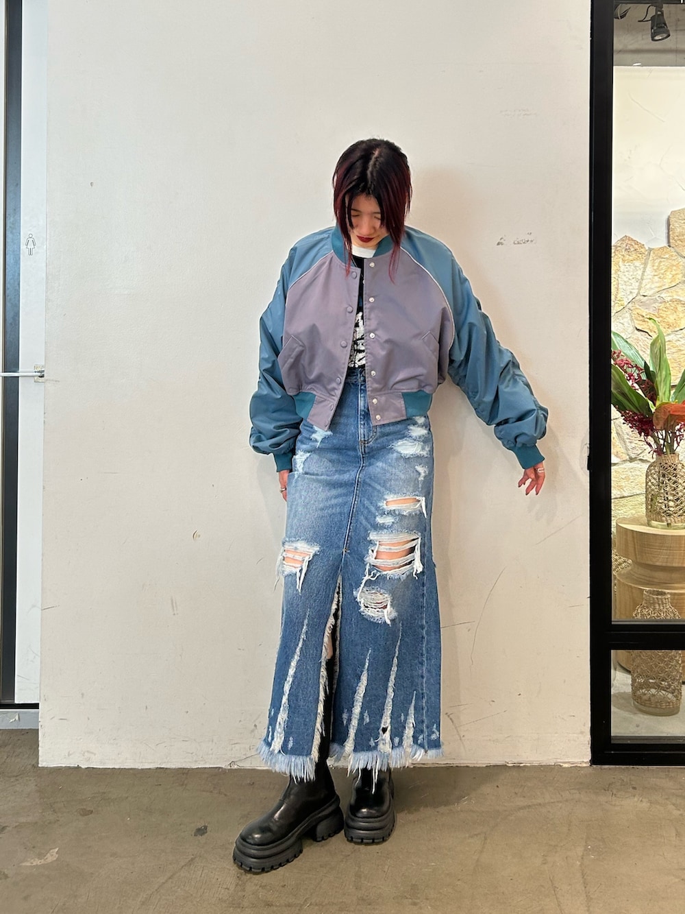 ブラック系のブーツ、グレー系のブルゾン、ブルー系のデニムスカートを着用したレディースの春コーディネートの2枚目の写真