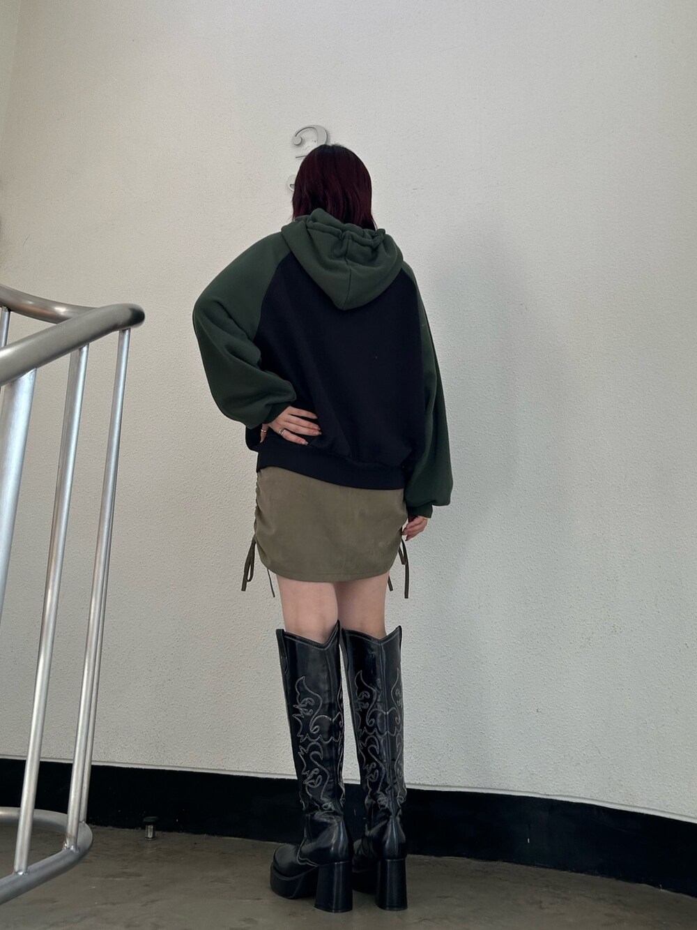 ブラック系のブーツ、グリーン系のスカート、ブラック系のパーカーを着用したレディースの冬コーディネートの3枚目の写真