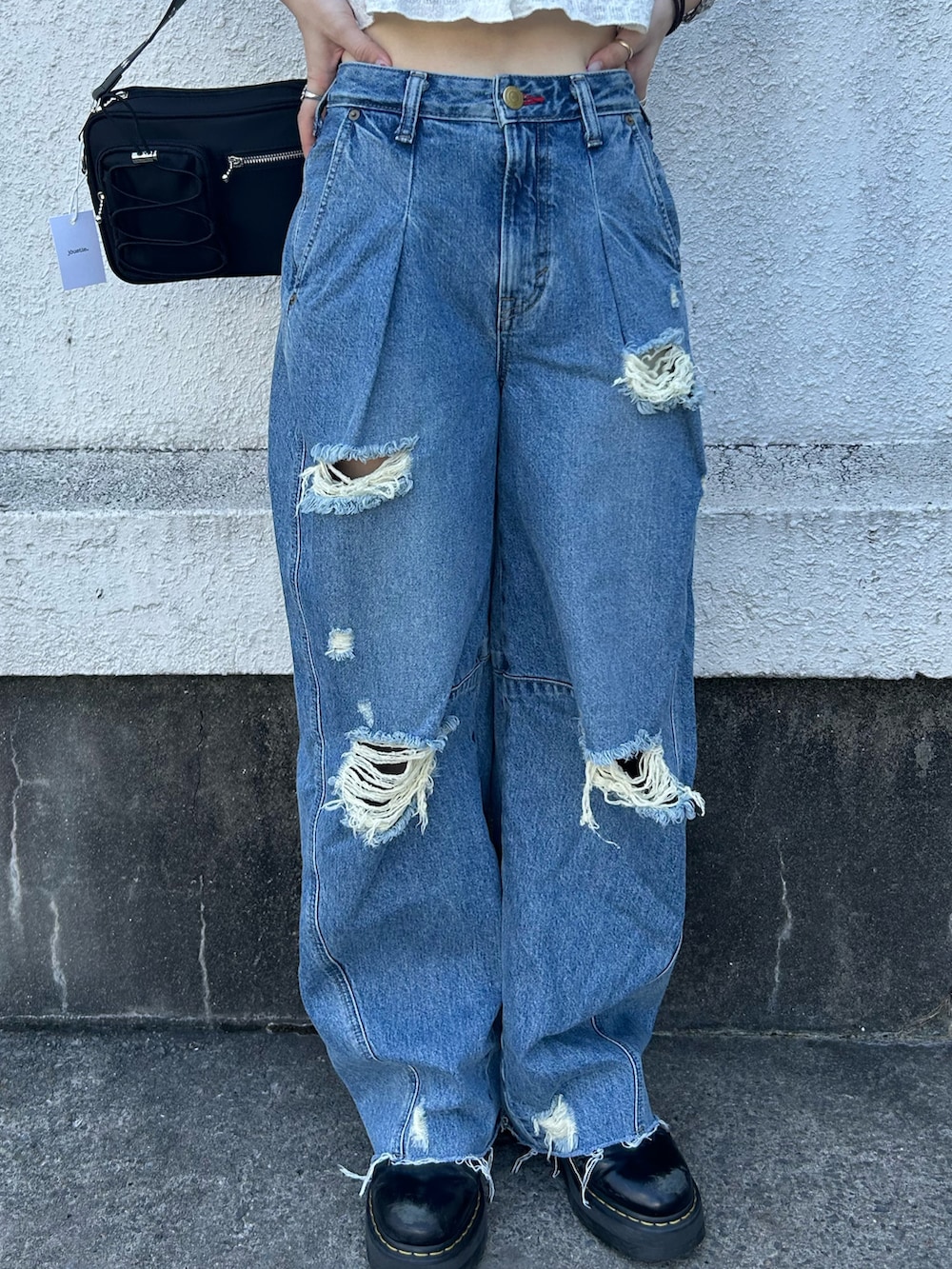 ブルー系のデニムパンツ、ブラック系のブーツ、ブラック系のショルダーバッグを着用したレディースの秋コーディネートの7枚目の写真