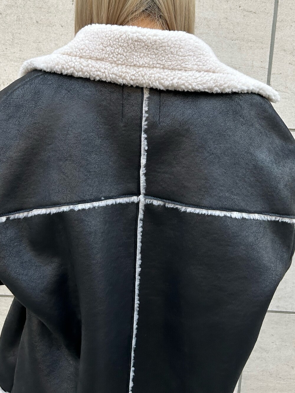 ブラック系のムートンコート、ブラック系のデニムパンツ、ブラック系のブーツを着用したレディースの秋コーディネートの7枚目の写真