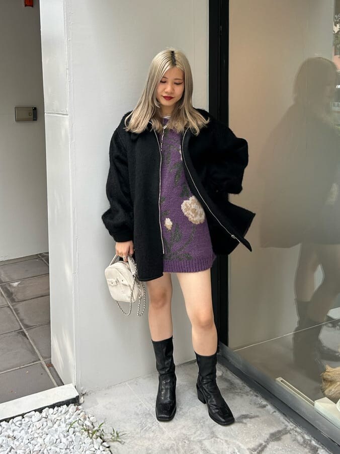 ブラック系のブーツ、ホワイト系のハンドバッグ、ブラック系のデニムパンツを着用したレディースの秋コーディネートの2枚目の写真