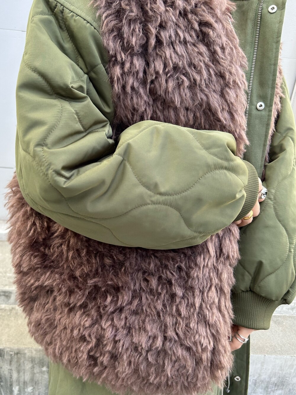 グリーン系のモッズコート、レッド系のニット/セーター、ホワイト系のTシャツ/カットソーを着用したレディースの秋コーディネートの7枚目の写真