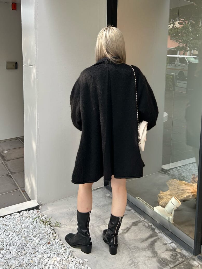 ブラック系のブーツ、ホワイト系のハンドバッグ、ブラック系のデニムパンツを着用したレディースの秋コーディネートの4枚目の写真