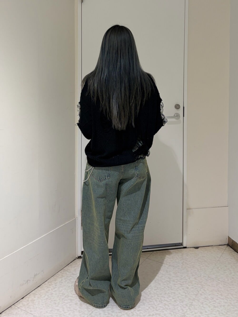 ブルー系のデニムパンツ、ブラック系のニット/セーター、シルバー系のネックレスを着用したレディースの春コーディネートの4枚目の写真