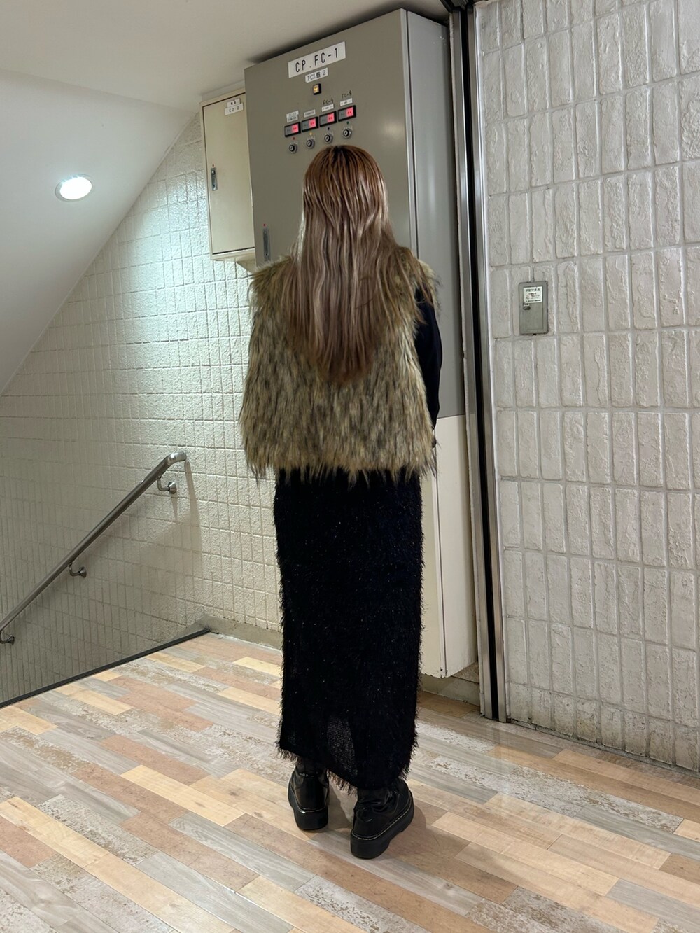 ブラック系のスカート、ブラック系のブーツ、ベージュ系のベストを着用したレディースの秋コーディネートの3枚目の写真