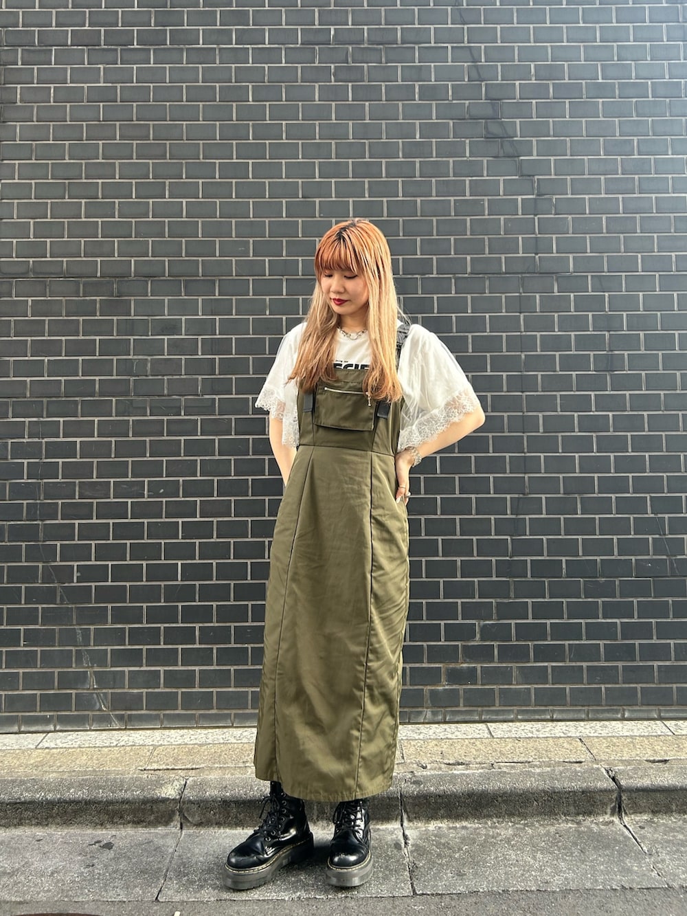 ブラック系のブーツ、グリーン系のジャンパースカート、ホワイト系のTシャツ/カットソーを着用したレディースの夏コーディネートの2枚目の写真