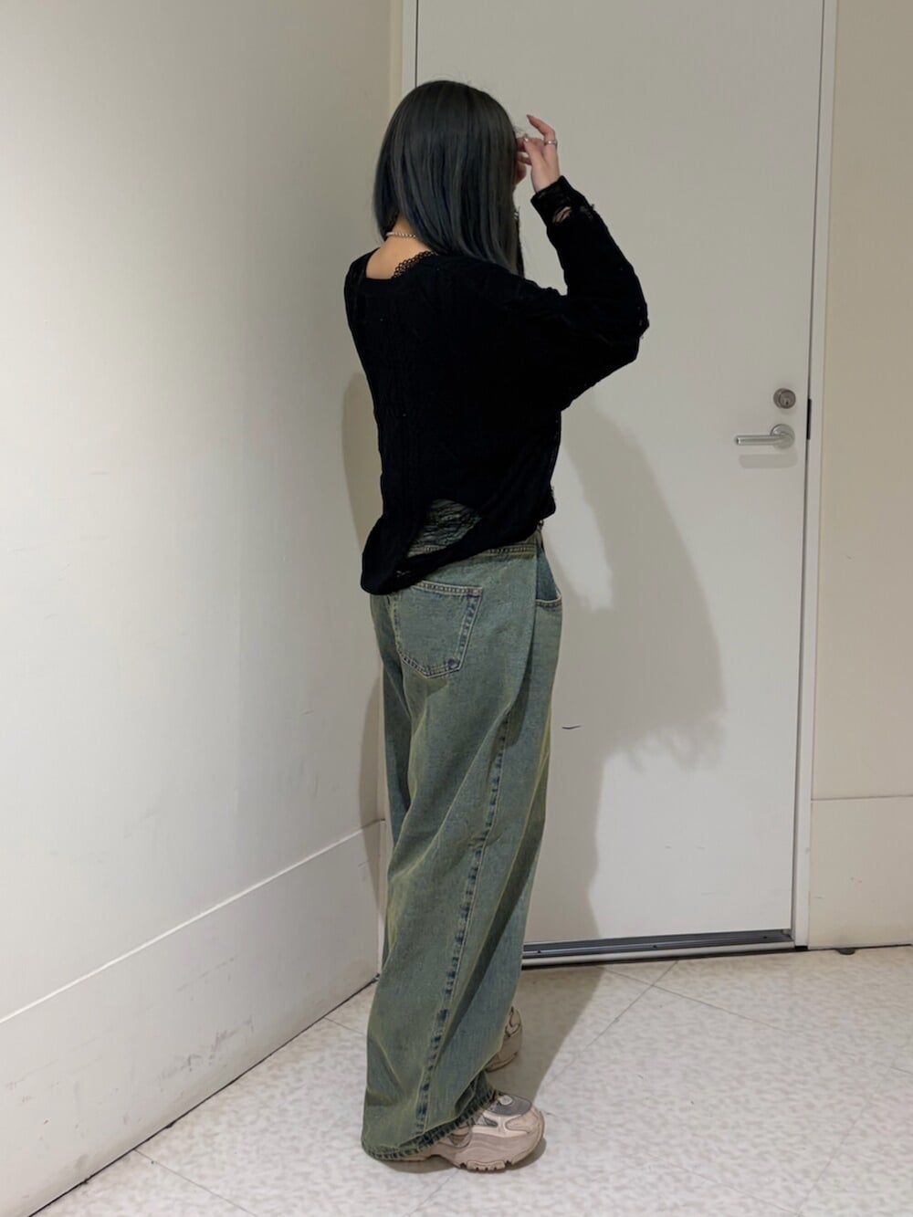 ブルー系のデニムパンツ、ブラック系のニット/セーター、シルバー系のネックレスを着用したレディースの春コーディネートの3枚目の写真