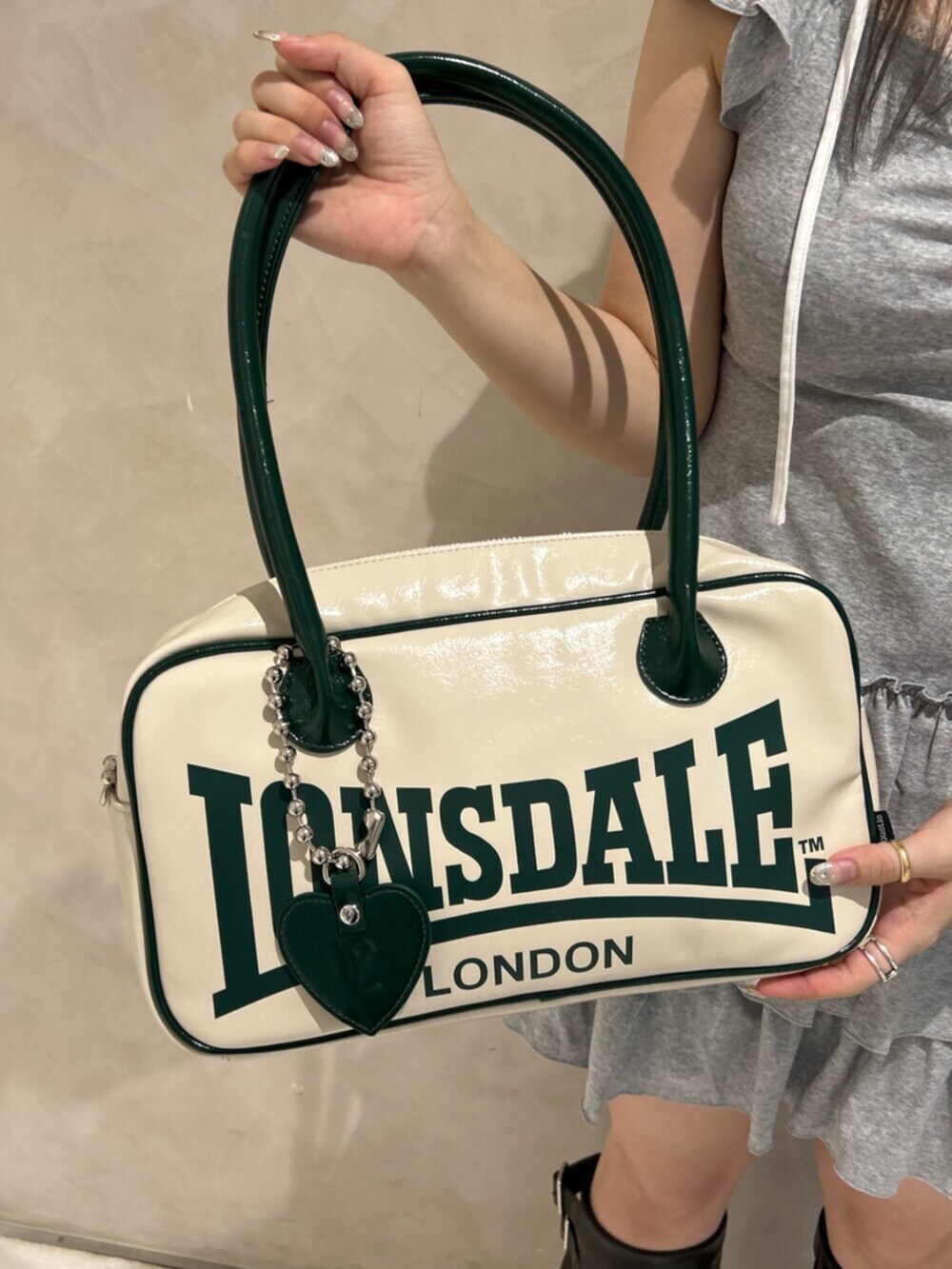 ブラック系のブーツ、グレー系のワンピース、ホワイト系のボストンバッグを着用したレディースの秋コーディネートの6枚目の写真