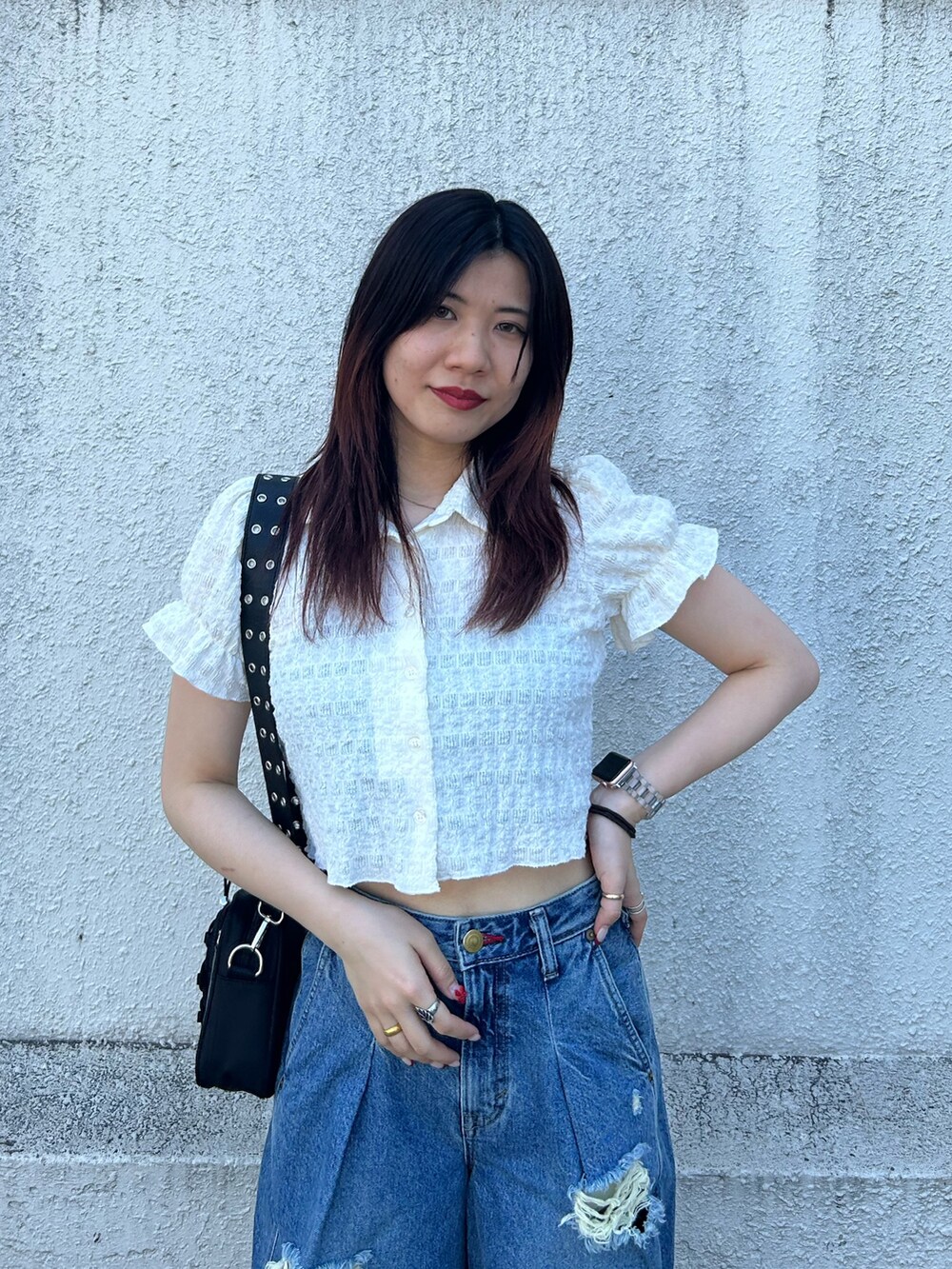 ブルー系のデニムパンツ、ブラック系のブーツ、ブラック系のショルダーバッグを着用したレディースの秋コーディネートの4枚目の写真