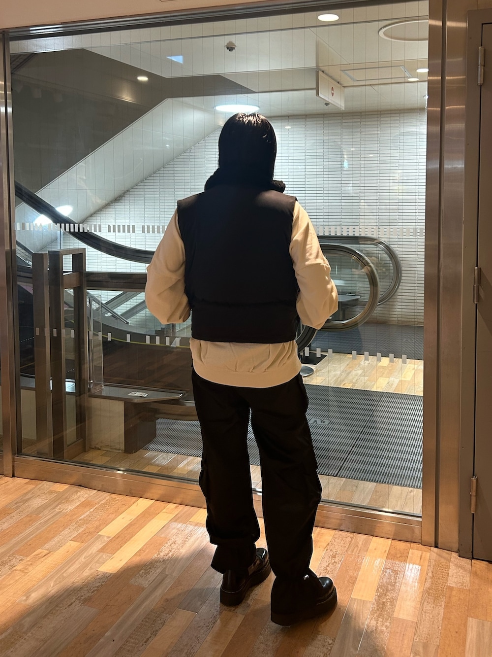 ブラック系のブーツ、ブラック系のダウンベスト、ホワイト系のTシャツ/カットソーを着用したレディースの秋コーディネートの3枚目の写真