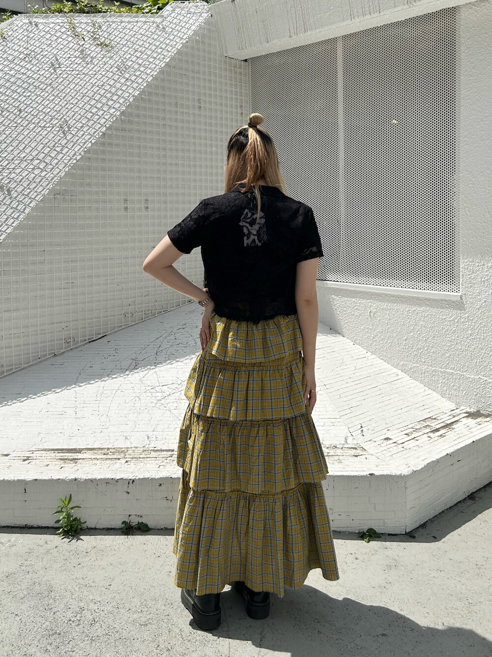 ブラック系のブーツ、イエロー系のスカート、ブラック系のTシャツ/カットソーを着用したレディースの春コーディネートの3枚目の写真