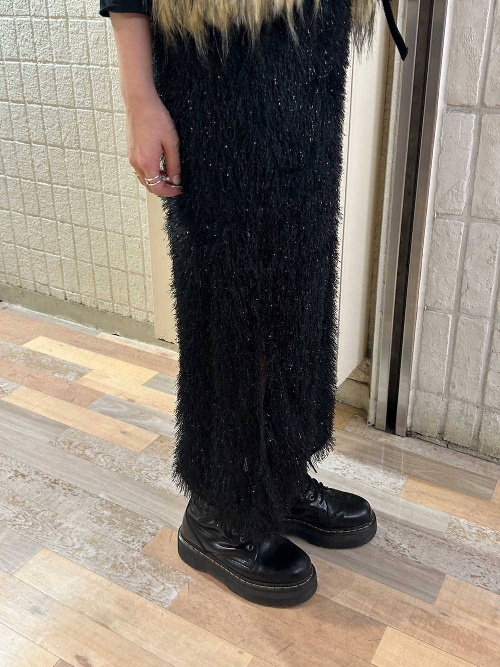 ブラック系のスカート、ブラック系のブーツ、ベージュ系のベストを着用したレディースの秋コーディネートの7枚目の写真